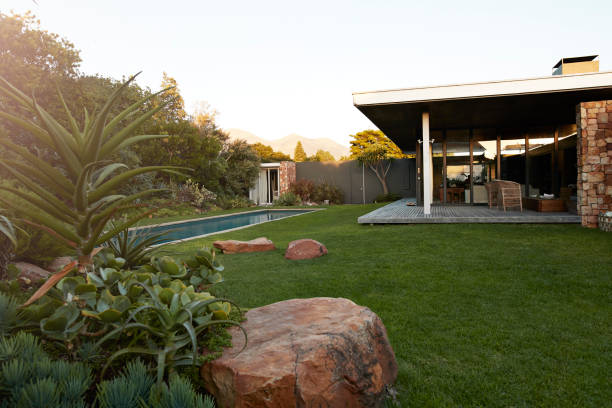 Grand jardin avec belle pelouse, piscine creusée, terrasse et pierres.