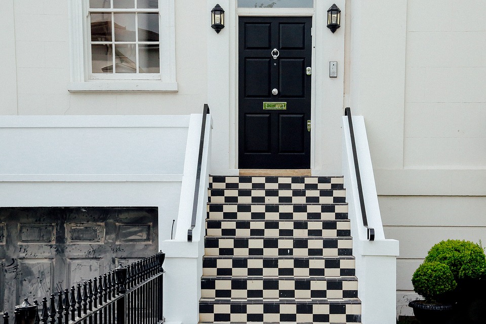 Porte d'entrée noire d'une maison moderne avec escalier noir et blanc